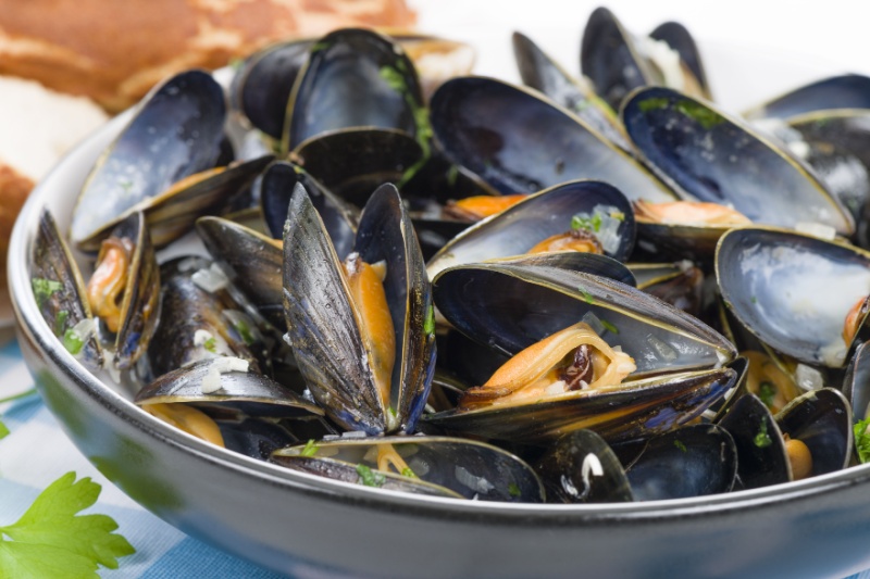 a bowl of cooked black mussels